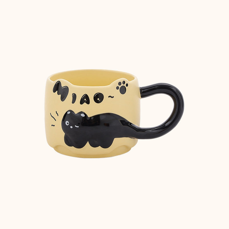 Warm yellow black cat ceramic mug on a plain cream background - 3D relief black cat draped around the body, cat-ear rim, glossy black tail handle, and hand-painted MIAO lettering
