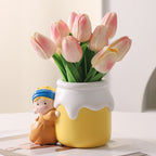 Girl with a Pearl Earring vase full of pink blush tulips on a white table - cute resin figurine of the girl in blue headscarf and mustard dress hugging a butter-yellow milk jar vase with white drip-glaze rim, soft daylight