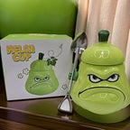 Grumpy Melon Cup gift set on a wooden desk - a 3D sculpted grumpy green melon ceramic mug with its lid on, a shovel-shaped spoon hanging on the rim, and the cheerful green and white Melon Cup gift box behind