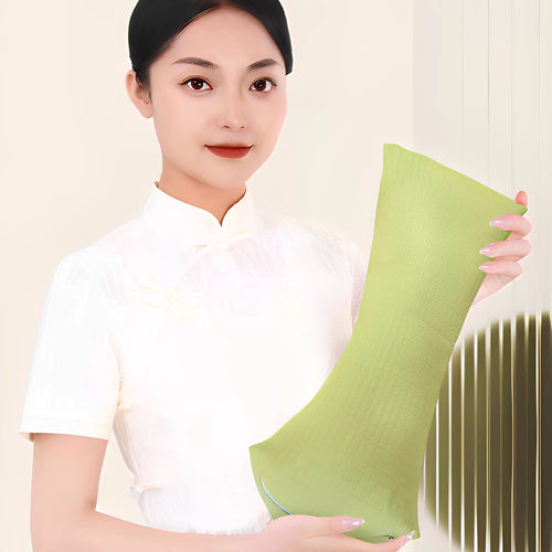 Woman in a white qipao top holding up the green buckwheat triangle neck pillow to show its size - lime green wedge pillow with quilted puff texture and white piping, curved silhouette visible, cream wall behind