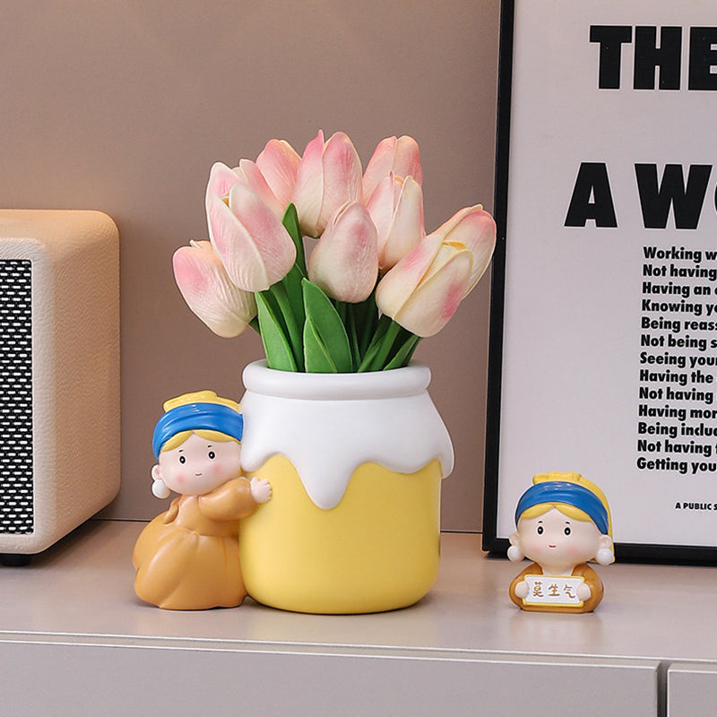 Girl with a Pearl Earring vase holding pink tulips on an entryway shelf - resin girl in blue headscarf hugging the yellow jar vase, a small matching figurine holding a sign beside her, framed poster and radio behind