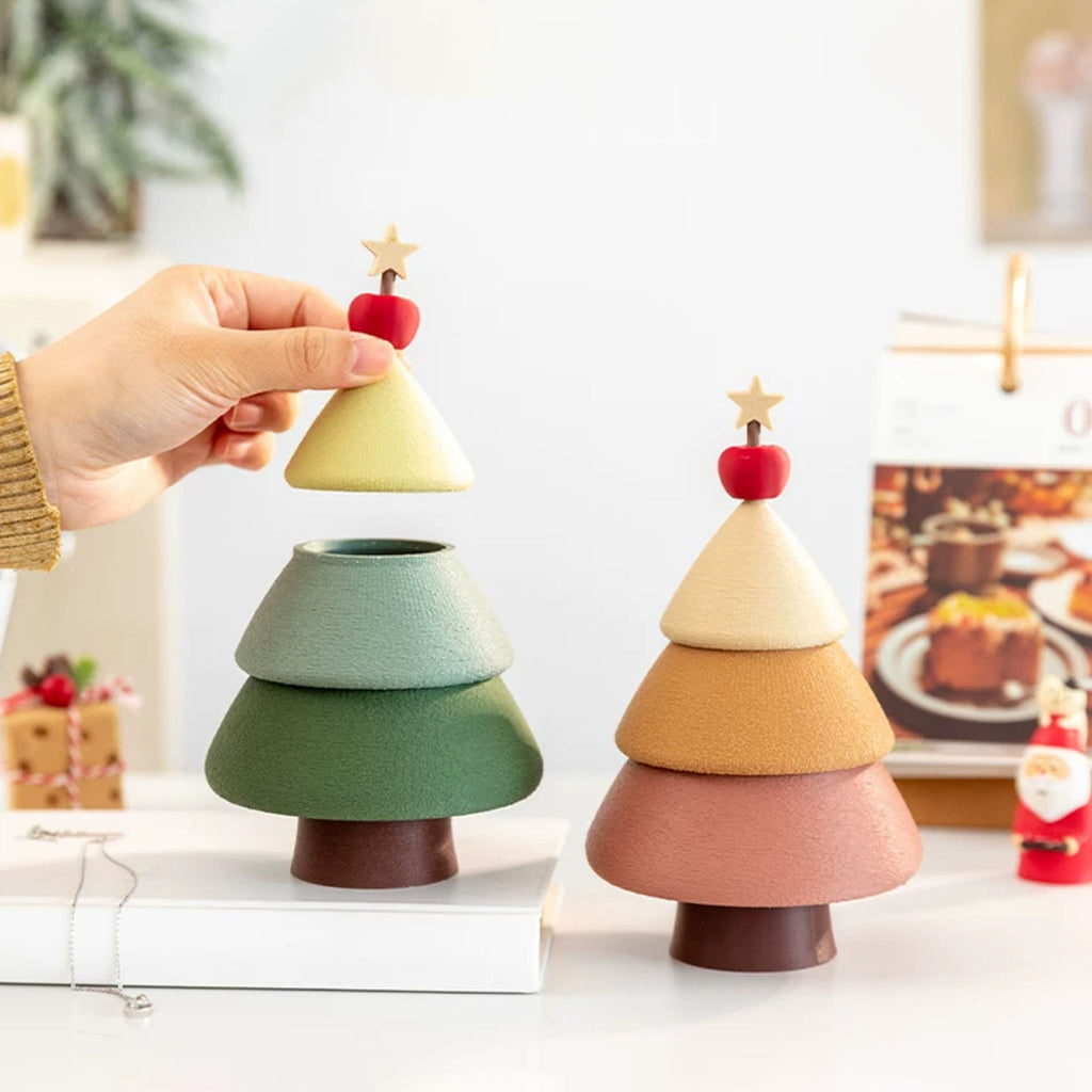 Hand lifting the top tier off the green Christmas tree jewelry box while the cinnamon version sits beside it - showing the hidden storage opening and stacked tier design of the 3D printed tree