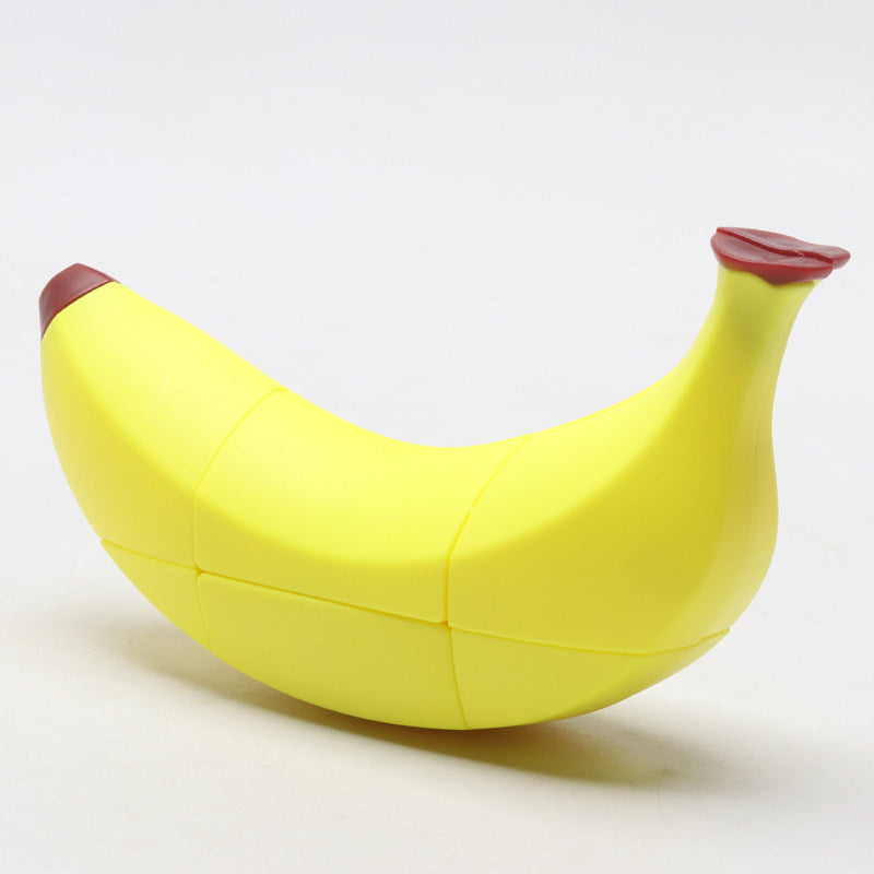 Yellow banana shape cube puzzle on a white background - 3x3 twisty cube moulded as a curving banana with dark red tips at both ends, stickerless yellow panels with turning seams