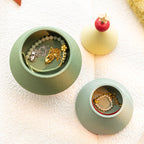Top-down view of the green Christmas tree jewelry box opened into two storage tiers - necklaces and gold chains coiled in the deep compartment, pearl bracelet in the shallow tray, star topper resting beside