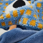 Close-up of the blue and mustard check lamb-wool jacquard shell of the Eye Guy pillow blanket, showing the fluffy sherpa texture, embroidered eye detail, and the zipper opening with the soft blue flannel blanket inside
