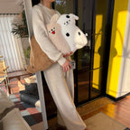 Person standing at a mirror holding two long-body dog hug pillows - cream tongue-out puppy and spotty white puppy, with a brown retriever pillow tucked under her arm