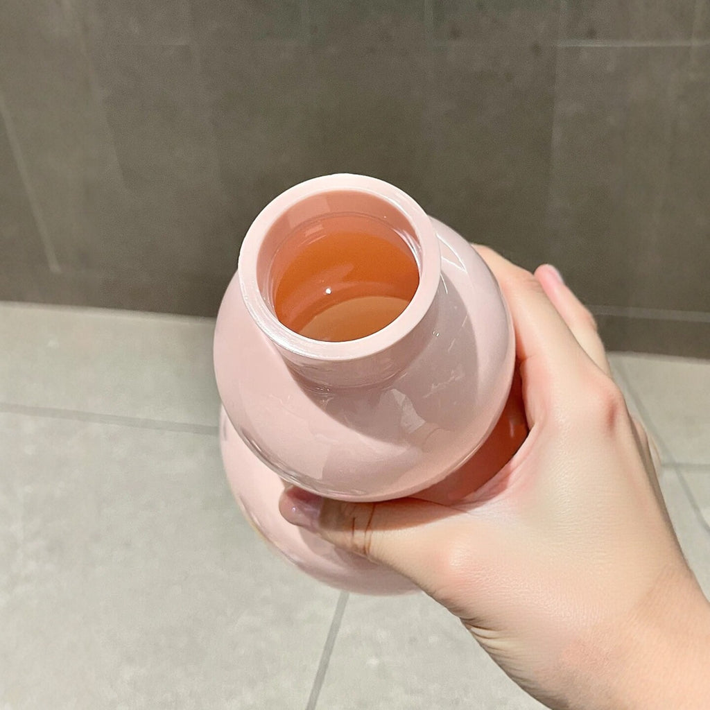 Top-down view into the open mouth of the pink gourd water bottle held by hand - showing the orange-tinted interior, wide threaded opening and glossy pink PC shell
