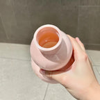 Top-down view into the open mouth of the pink gourd water bottle held by hand - showing the orange-tinted interior, wide threaded opening and glossy pink PC shell