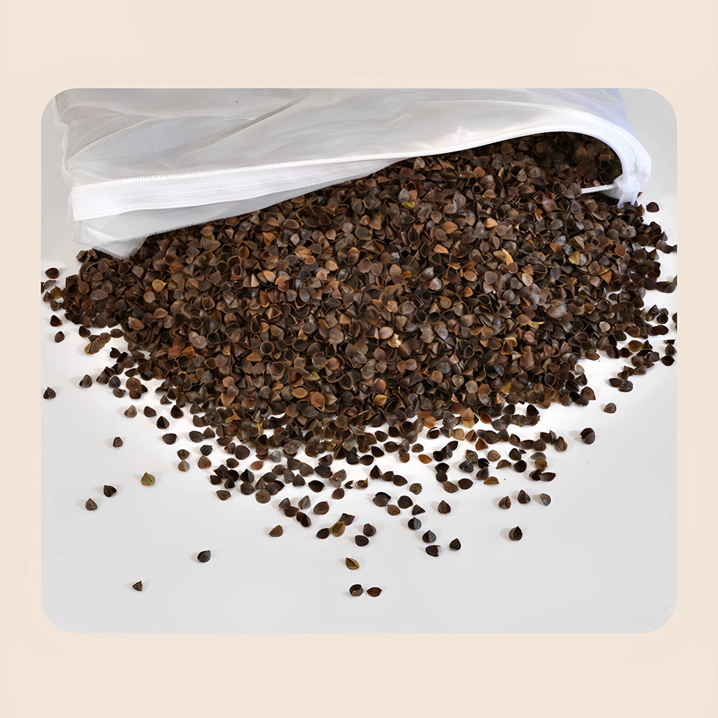 Brown buckwheat hulls spilling out of a white mesh inner liner bag on a white surface - natural pillow filling showing the hull texture, some hulls scattered in front of the opened drawstring liner