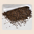 Brown buckwheat hulls spilling out of a white mesh inner liner bag on a white surface - natural pillow filling showing the hull texture, some hulls scattered in front of the opened drawstring liner