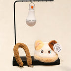 Product display of the plush night light charm on a black stand - the white LED bulb hanging lit from the top bar, the calico cat plush topper and detached fluffy caramel hang loop placed below, showing how the light detaches for washing