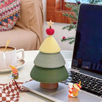 Green Christmas tree jewelry box on a laptop keyboard edge beside a coffee cup - matte frosted 3D printed tree with sage and cream tiers, red apple and star topper, cozy winter desk scene
