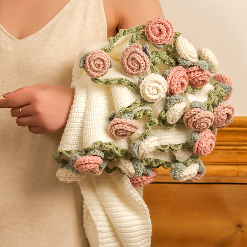 Cream knit blanket folded into a bouquet of blush-pink and white roses, held in a woman's arms ready to gift.